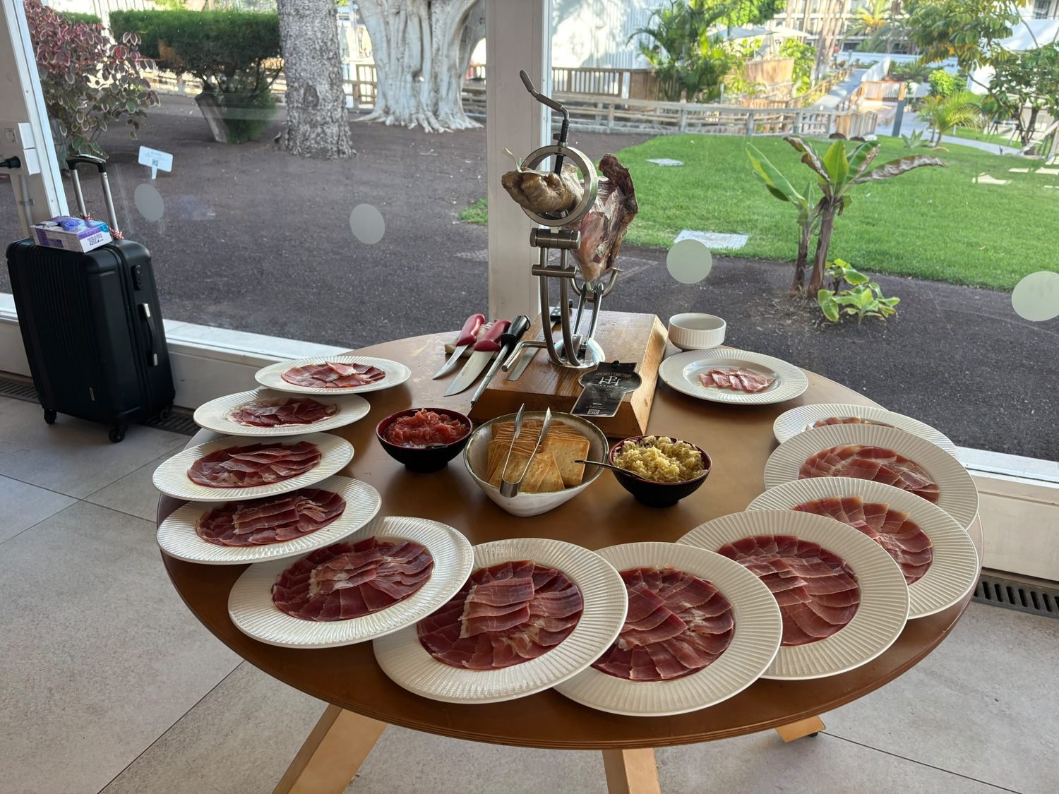 Mesa de buffet con jamonero, platos de jamón cortado, pan y acompañamientos