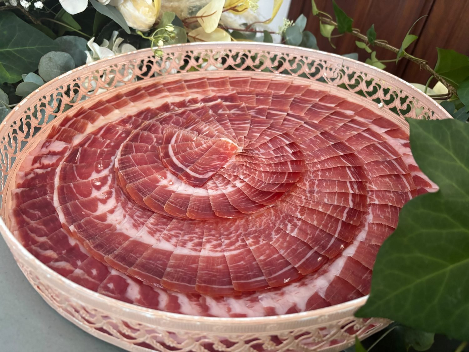Bandeja redonda de borde calado cubierta con lonchas de jamón superpuestas