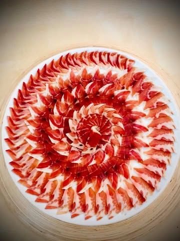 Bandeja circular de madera con lonchas de jamón dispuestas en roseta