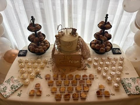 Mesa dulce con tarta de pisos y postres individuales montada para una celebración