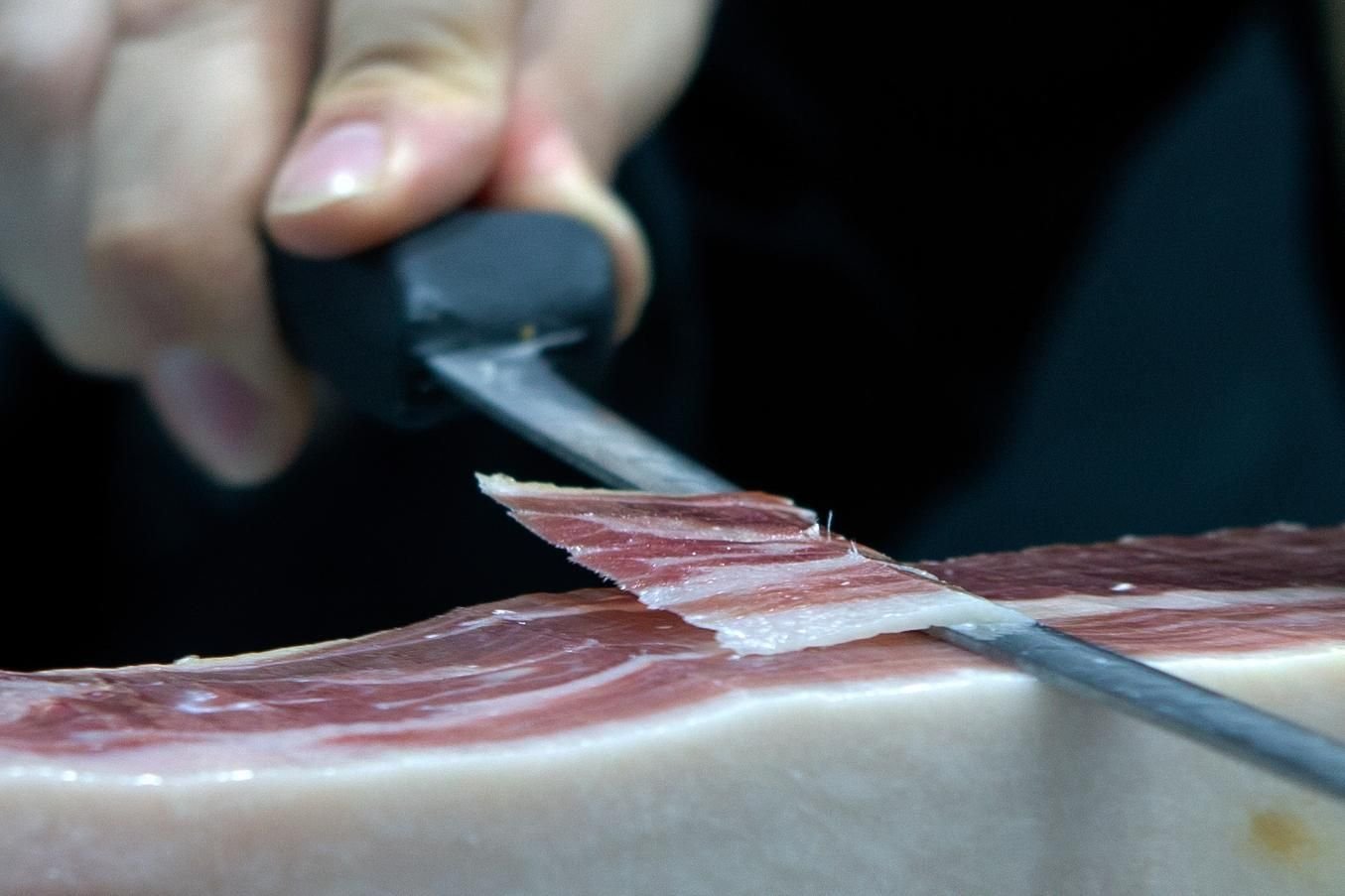 Cortador de jamón profesional loncheando un jamón con cuchillo largo