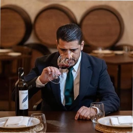 José María Sánchez, con traje, catando el aroma de una copa de vino tinto